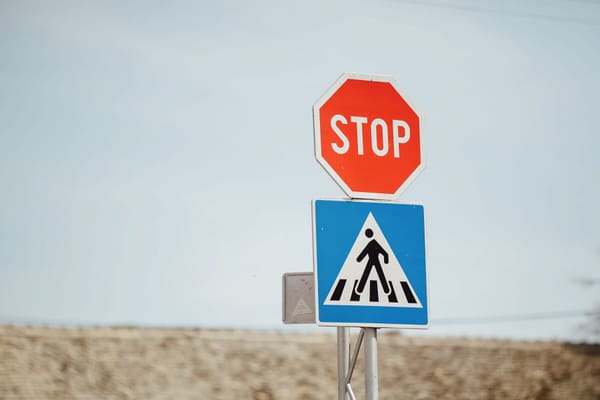 A crosswalk sign with a stop sign above it.
